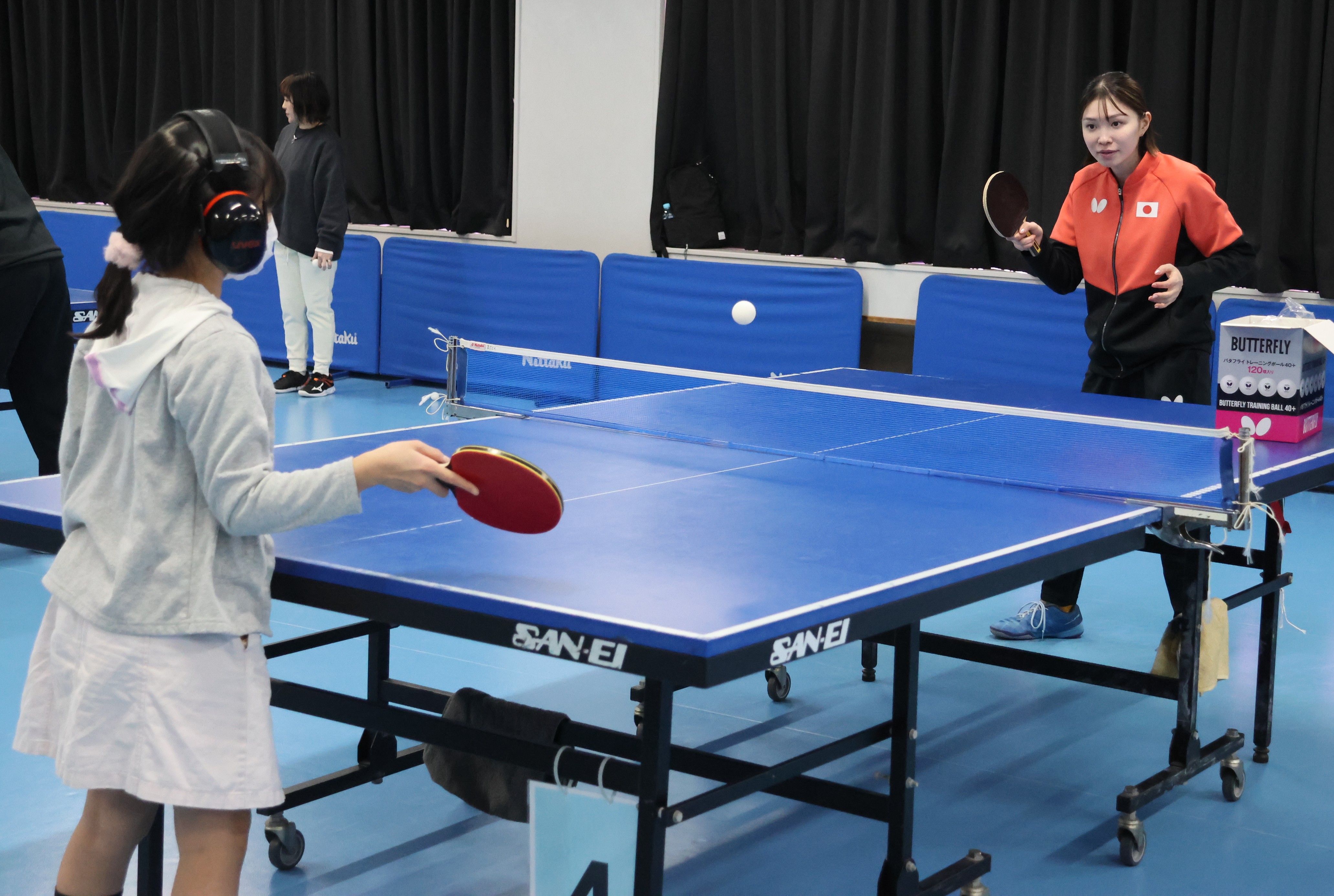 参加者がヘッドフォンを装着して山田選手と「デフ卓球」対戦
