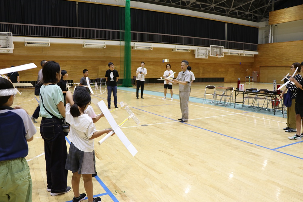 紙ヒコーキの飛ばし方を習う様子